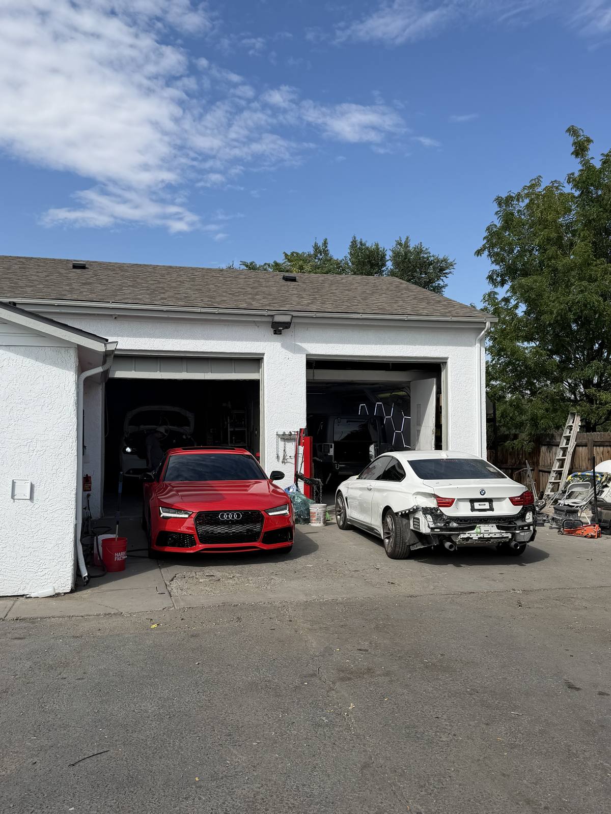 The shop on Quebec Street with both bay doors open, a car parked at each.