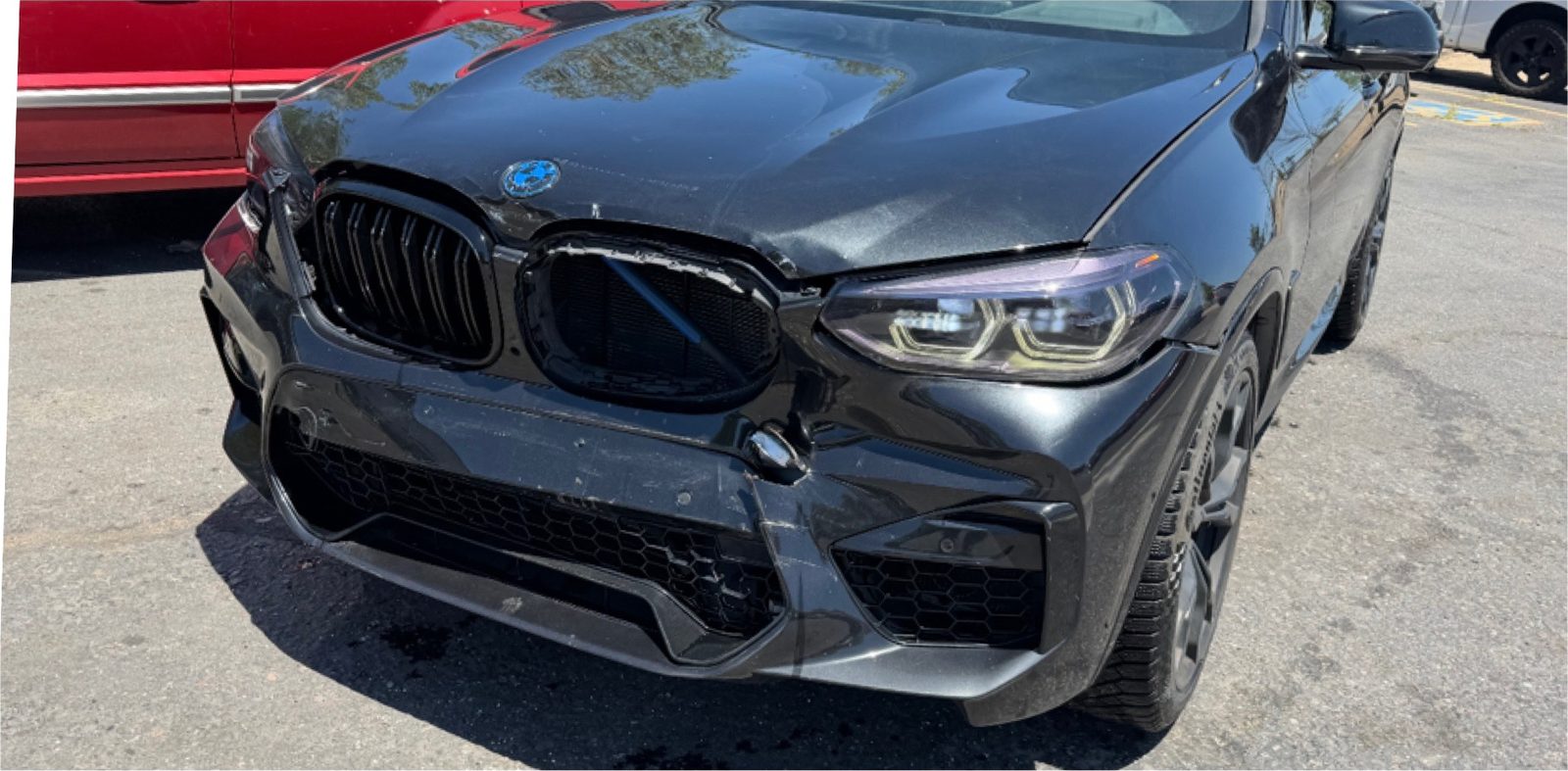 Black BMW X4 M with damage to the front bumper, grille and fender.