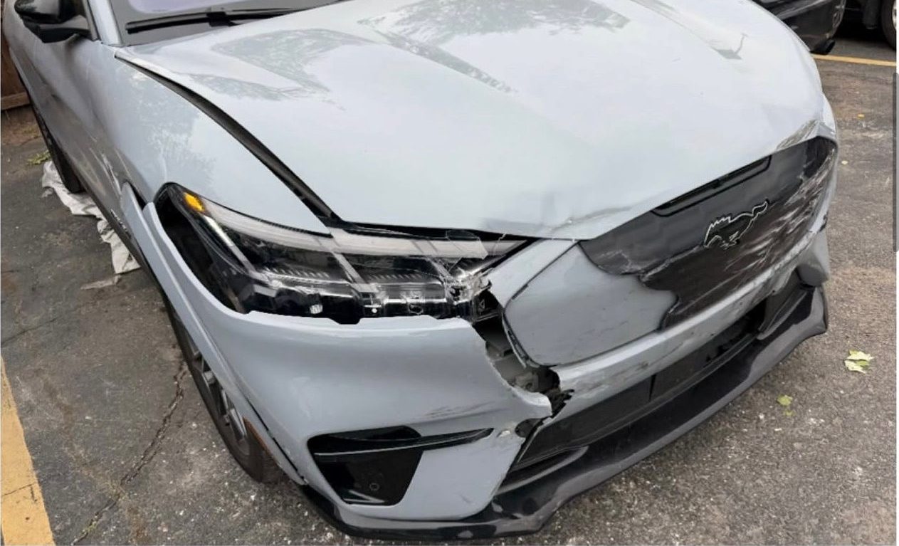 Light grey Ford Mustang Mach-E with the front bumper and headlight assembly broken open.