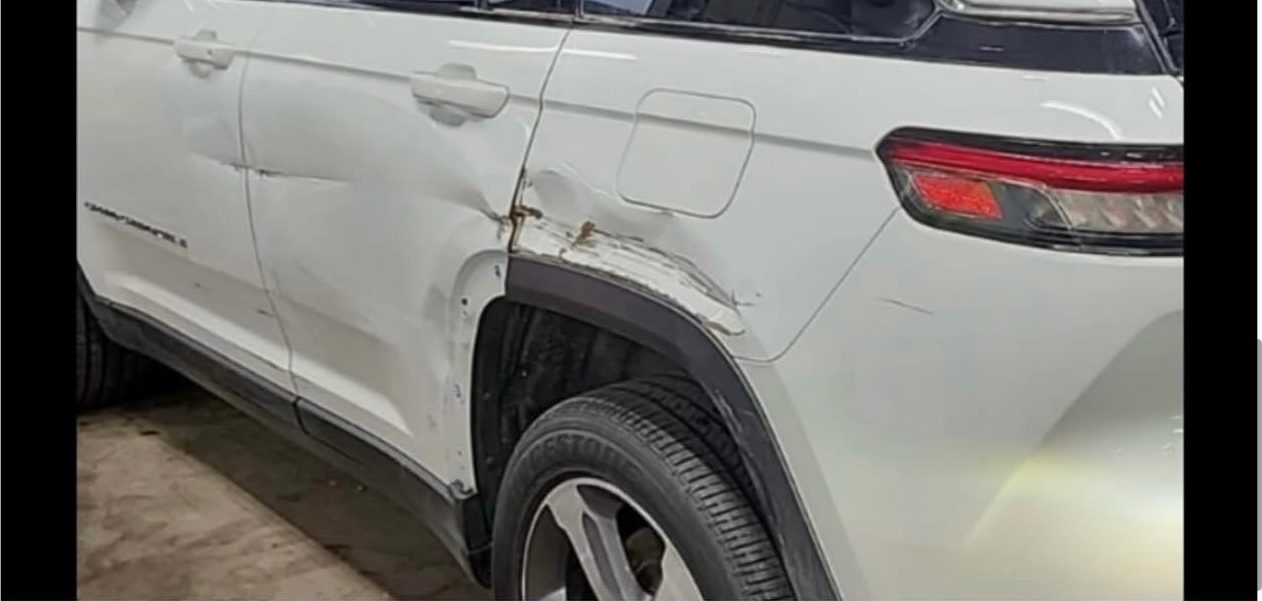 White Jeep Grand Cherokee 4xe with a deep crease through the rear door and quarter panel.