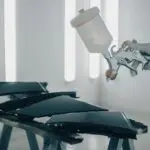 Close-up of car parts being spray-painted in an automotive workshop.